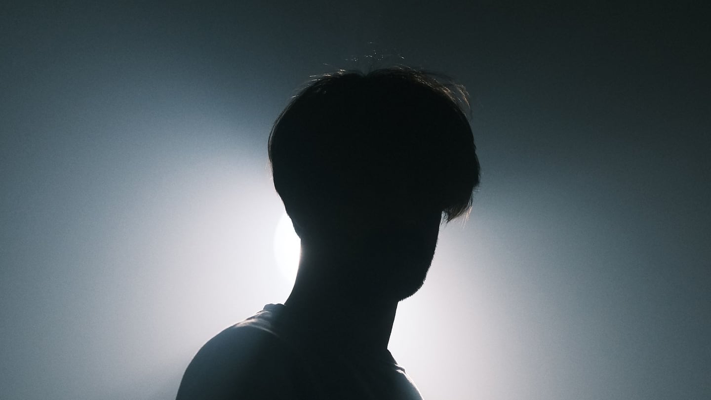 A person in silhouette against dramatic backlight, rimmed by a bright halo